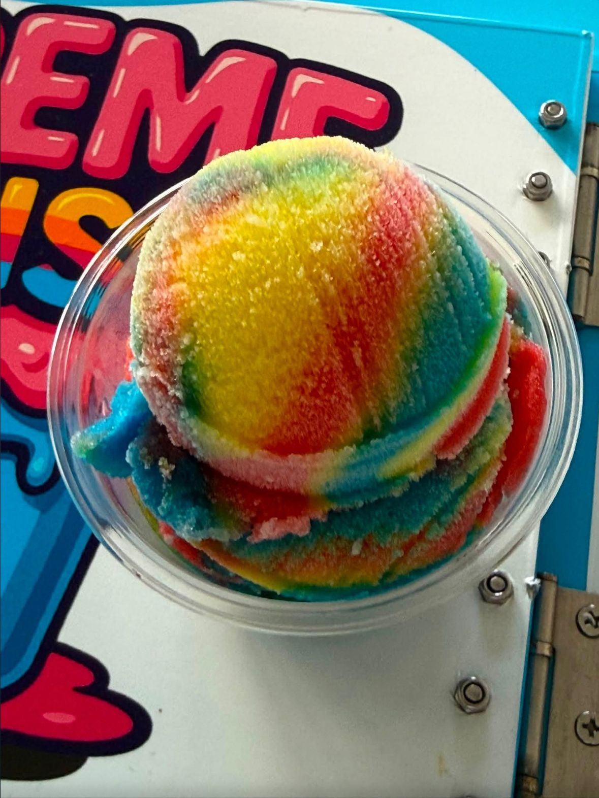 A cup of rainbow water ice with red, yellow, green and blue layers on the Kreme Cruiser cart