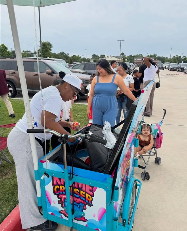 A Kreme Cruiser server scooping water ice for families waiting at an outdoor community event