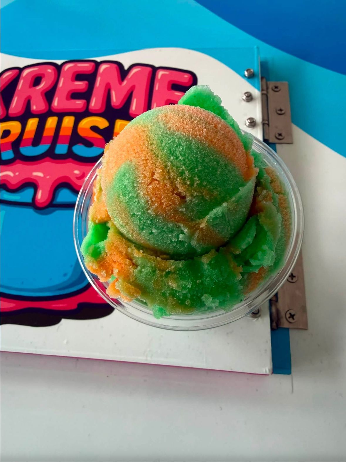 A cup of orange and green water ice on the Kreme Cruiser cart